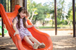 © bongkarn - A playful and cheerful young Asian girl is playing a colorful slide in a playground in the park.