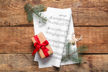 Poster - Composition with music sheets, Christmas gift and fir branches on wooden background