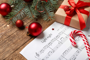 Wall Mural - Composition with music sheets, Christmas gift and decorations on wooden background, closeup