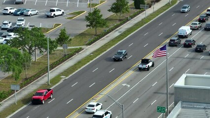 Wall Mural - Aerial view of wide multilane road with moving cars and waving US flag. City transportation in the USA. American urban traffic from above