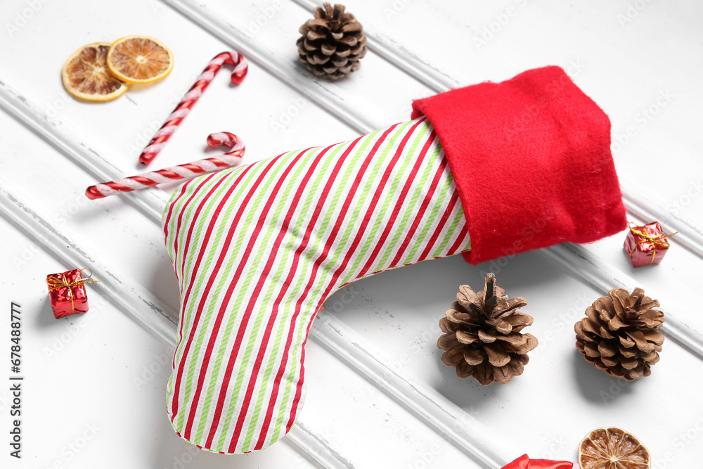 Christmas sock with candy canes, cones and dried orange on white background
