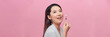 Beautiful asian woman massaging face with jade roller isolated on pink background