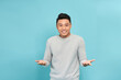 Excited surprised handsome young Asian man doing open hand gesture isolated on blue background
