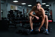 © Михаил Решетников - Muscular shirtless man sitting on a bench and lifting a dumbbell.