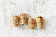 Aesthetic still life New Year, xmas minimal style trend flat lay, wine corks champagne sparkling wine on white fur as shiny snow, bottle stoppers festive drink, sequins gold star, winter holidays