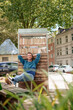 © Westend61 - Smiling man sitting and leaning on cabinet of books