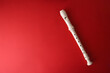 White plastic recorder on red gradient background