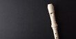 Musical background with detail of white plastic recorder on black