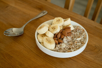 Canvas Print - Oatmeal with banana, honey and almonda for breakfast on a table