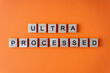 © Real_life - Word ultra processed. The phrase is laid out in wooden letters top view. Orange flat lay background