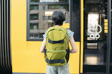 View back from the teenage girl with green backpack waiting for the streetcar at the station