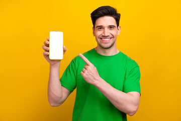 Wall Mural - Portrait of young handsome smiling guy wear green t shirt promoting new smartphone website ai service isolated on yellow color background