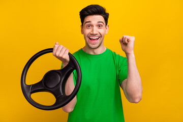 Wall Mural - Photo portrait of nice young brunet male shocked excited hold rudder wear trendy green garment isolated on yellow color background