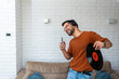Young happy man singing and dancing at home listening music on wireless headset singing on his phone holding LP record in his hand. Hipster music lover digitized old record audio and enjoying