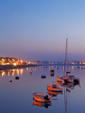 Fototapeta  - Seixal Bay with small boats and a sailing trimaran at twilight, nightfall, dusk or evening. Setubal, Portugal