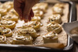 © weyo - Female cooks hands sprinkle sesame on raw mini cakes before baking.