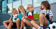 © serg - Happy caucasian school friends talking and doing homework, having fun during break sitting on stairs at school building background, outdoor. Back to school concept