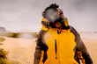 © simona - Standing explorer adventure man walking down the rain at the beach. Concept of bad weaterh nature and feeling. Male people with yellow jacket in outdoor leisure activity