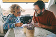 © simona - Adult couple planning next travel destination sitting inside a camper van using a paper map guide on the table. ature traveler and vanlife alternative people lifestyle. Couple of tourist and beach