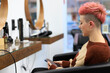 Woman sitting in hairdresser while looking at social networks on mobile