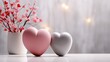  three heart shaped vases sitting next to each other on a table with pink flowers in the vase and a white vase with pink and red flowers in the middle.