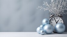  A Clock Sitting On Top Of A Table Next To Blue Balls And A Bunch Of Silver And White Balls In Front Of A Light Blue Background With A Gray Wall.