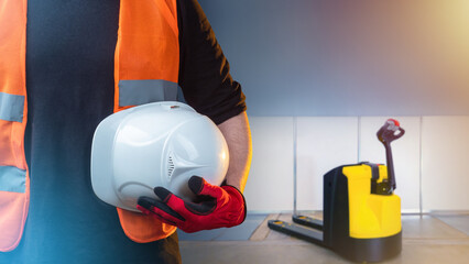 Poster - Hardhat in hand of warehouse worker. Electric forklift near cropped men. Warehouse employee guy. White hardhat to protect worker head. Warehouse inventory. Protective helmet in hand. Plastic hardhat