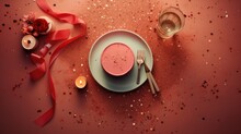  A White Plate Topped With A Cup Of Hot Chocolate Next To A Red Ribbon And A Candle On Top Of A Red Tablecloth Covered With Confetti And Sprinkles.