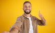 © Prostock-studio - Happy millennial european guy with beard in casual make thumb up hand sign, make selfie
