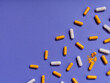 Top view pattern orange and white vitamin pills on violet background