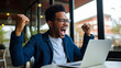 Ecstatic African American man celebrates online job success.
