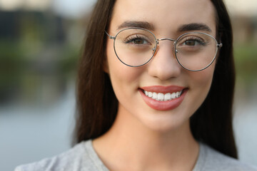 Wall Mural - Portrait of beautiful woman in glasses on blurred background. Attractive lady smiling and looking into camera