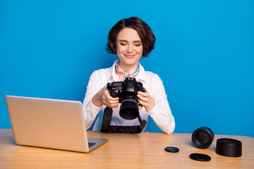 Sticker - Photo of satisfied lady sit behind desk hands hold camera look photos isolated on blue color background