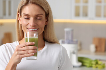 Canvas Print - Woman drinking fresh celery juice in kitchen. Space for text