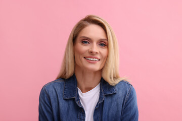 Canvas Print - Portrait of smiling middle aged woman with blonde hair on pink background