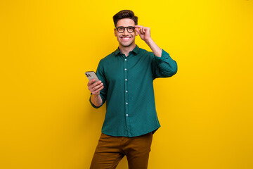 Photo of confident successful man wear green trendy clothes use modern device isolated on yellow color background