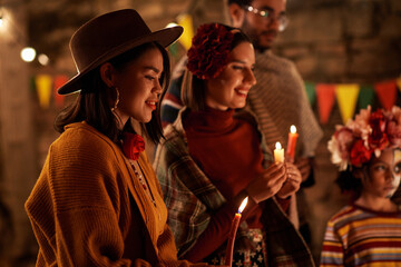 Wall Mural - Young woman with candles standing at altar and celebrating the day of dead together with other people