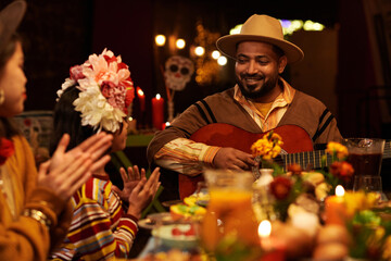 Wall Mural - Man playing guitar while sitting at table with his family and celebrating the traditional holiday