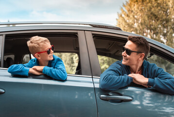 Wall Mural - Young father and son smiling having fun in car ready for a fun roadtrip holiday adventure. 