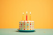 © Positive Click - A birthday cake with colorful icing and candles on a yellow background.