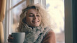 
Happy blond woman with bunch hairstyle warming and cover knitted plaid enjoying in her coffee time by the window in cold winter day. Peace of mind and mental health.