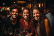 Frohe Gesellschaft - Mann und zwei junge Frauen lachen fröhlich in einer Bar