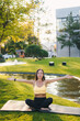 © Strelciuc - Adult woman sitting yoga pose with their hands outstretched out in city park on summer morning. Enjoying exercising at nature outside. Be healthy