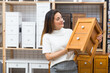 © JackF - Latino american woman buyer standing in furniture shopping room near chest of drawers