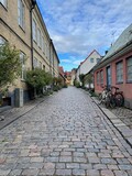 Fototapeta Uliczki - The narrow streets of Lund are traditional houses, bikes, and trees, against a background of sky