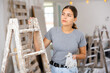 Portrait of positive young woman next to stepladder in a cottage room being renovated