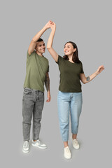 Wall Mural - Happy young couple dancing together on grey background