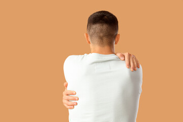 Sticker - Young man hugging himself on beige background, back view