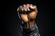 Black fist of a man in a leather jacket raised up in the air on a black background, black lives matter, racial injustice. Fighting racism. Human rights, struggle, protests against racism