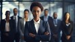 Confident African American businesswoman standing in front of team of business people working in the office looking at camera, executive manager female Afro hair wearing black suit arm crossed meeting